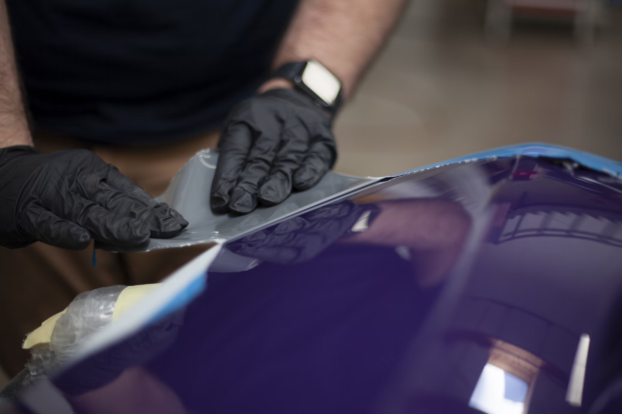 A person applies a protective film to a car.