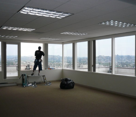 Professional installer applying commercial window tint to office windows to improve comfort and design.