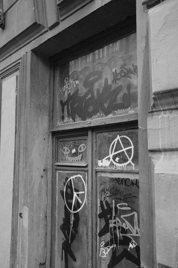 Storefront window vandalized with graffiti markings on glass.
