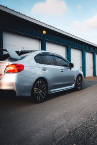 Silver sports sedan with dark window tint parked outside industrial garage units