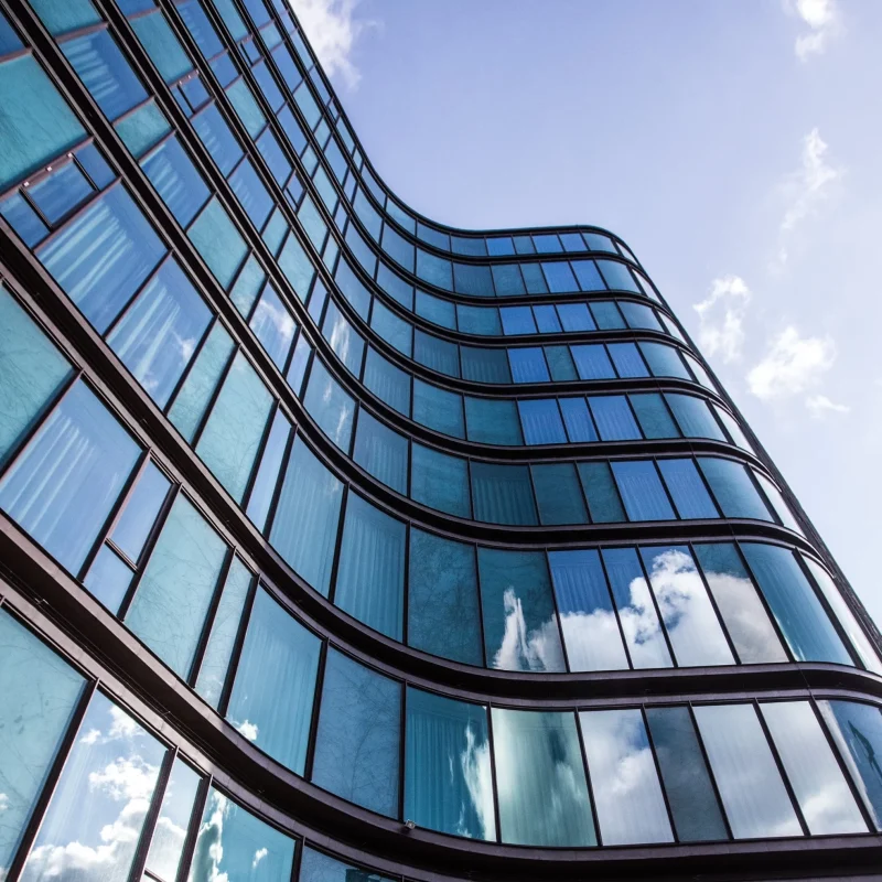 high rise building glass facade with reflection surrounding buildings